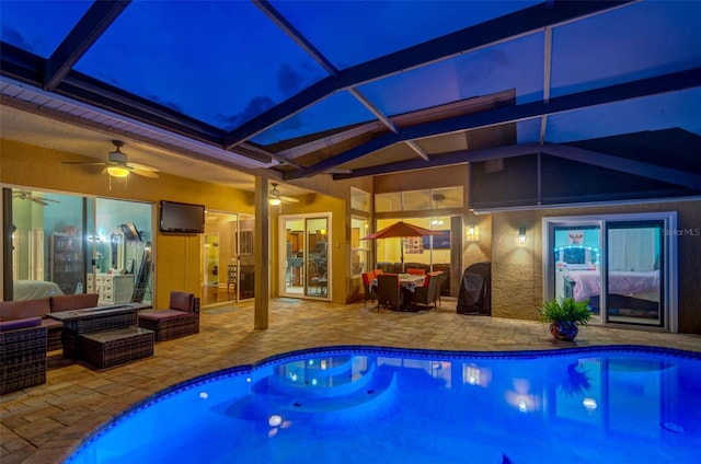 view of pool with ceiling fan, glass enclosure, outdoor lounge area, and a patio