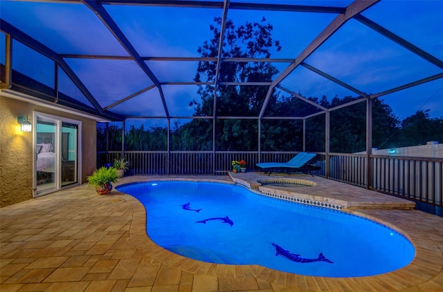 pool at dusk with a hot tub, a patio area, and glass enclosure