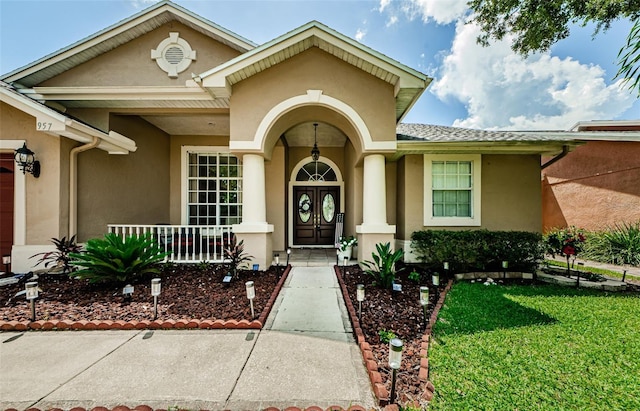 entrance to property with covered porch and a yard