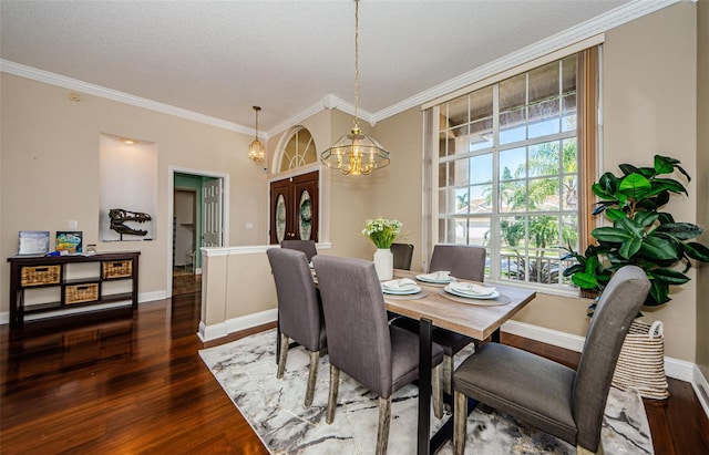 dining space with a textured ceiling, dark hardwood / wood-style flooring, crown molding, and a notable chandelier