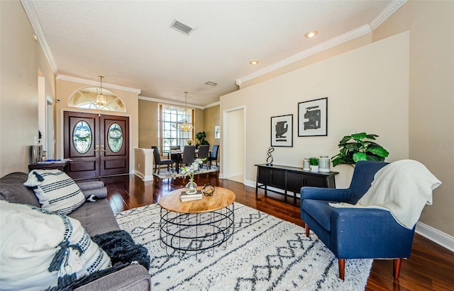 living room with dark wood-type flooring, a chandelier, and crown molding