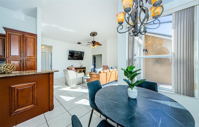 tiled dining area featuring ceiling fan with notable chandelier