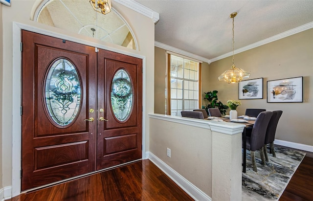 entrance foyer with an inviting chandelier, ornamental molding, and dark hardwood / wood-style floors