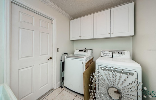 clothes washing area featuring washer and clothes dryer, ornamental molding, a textured ceiling, light tile patterned floors, and cabinets