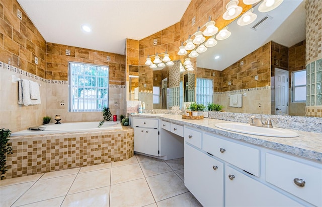 bathroom featuring vanity, tile walls, tile patterned floors, and a relaxing tiled tub