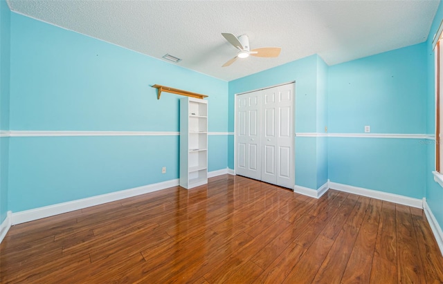 unfurnished bedroom with ceiling fan, a closet, a textured ceiling, and hardwood / wood-style flooring