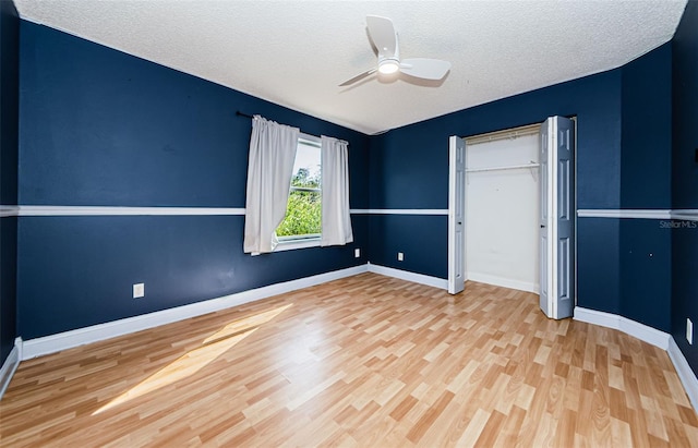 unfurnished bedroom with ceiling fan, a closet, a textured ceiling, and light hardwood / wood-style flooring