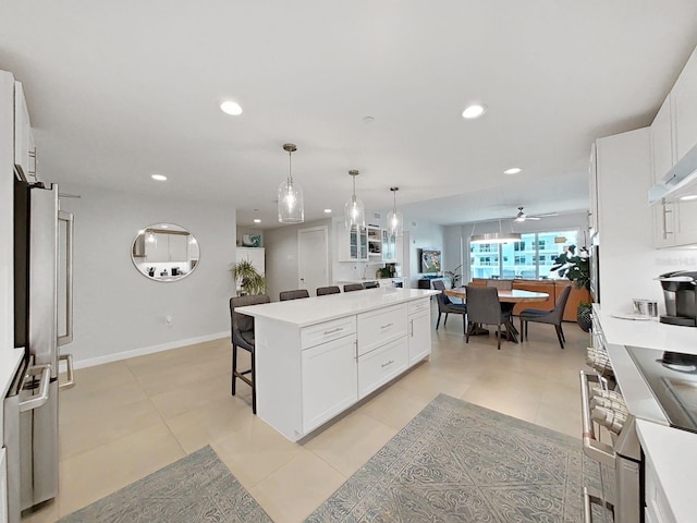 kitchen featuring a kitchen island, pendant lighting, white cabinets, and a kitchen bar