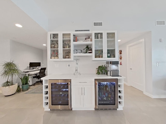 bar featuring beverage cooler, light tile patterned floors, and white cabinets