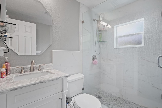 bathroom featuring vanity, a shower with shower door, and toilet