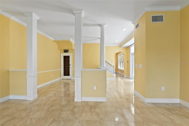 empty room featuring decorative columns, visible vents, and ornamental molding