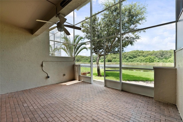 unfurnished sunroom with a wealth of natural light, a ceiling fan, and a water view