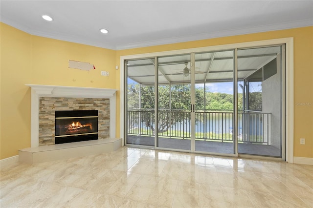 unfurnished living room featuring a fireplace, ornamental molding, ceiling fan, and a water view