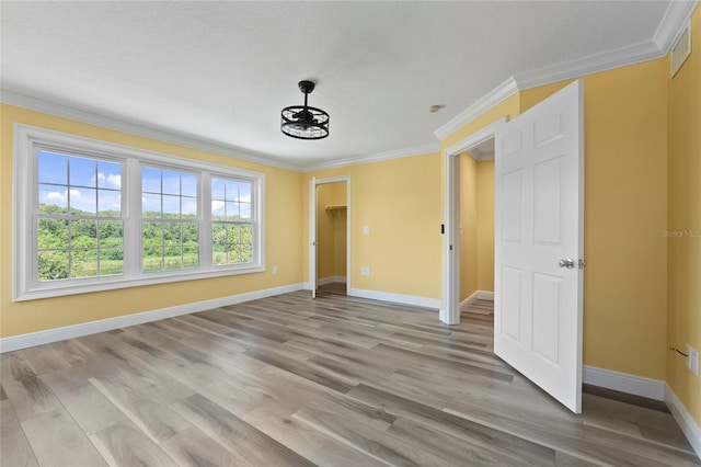 unfurnished bedroom with ornamental molding, a textured ceiling, light hardwood / wood-style floors, and a closet