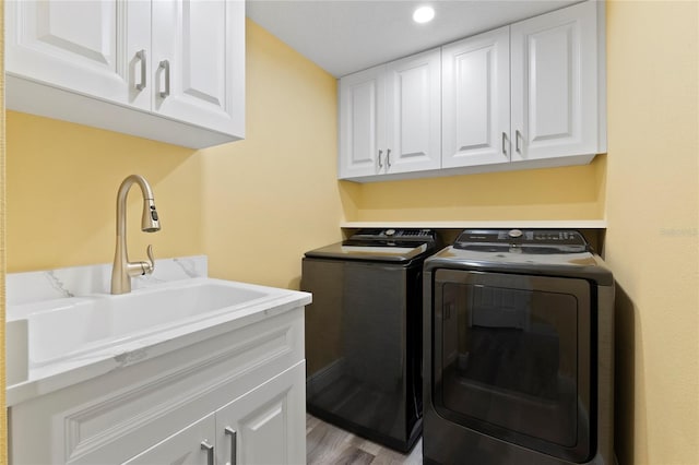 laundry room with washing machine and dryer, recessed lighting, light wood-style flooring, cabinet space, and a sink