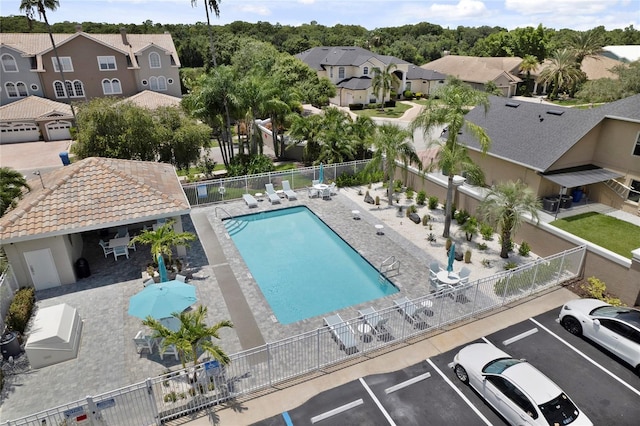 community pool featuring a patio, fence, and a residential view