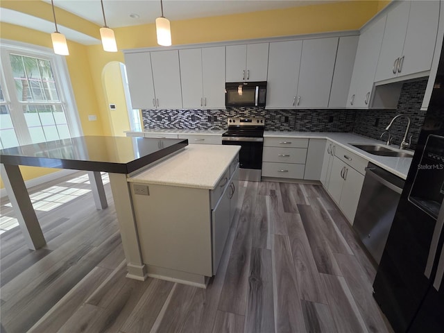 kitchen featuring a sink, stainless steel appliances, arched walkways, and dark wood finished floors