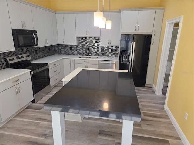 kitchen featuring a sink, stainless steel appliances, light countertops, light wood-style floors, and pendant lighting