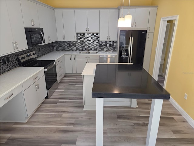 kitchen featuring light wood-type flooring, pendant lighting, a sink, backsplash, and stainless steel appliances