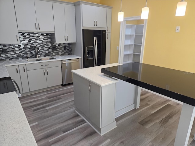 kitchen featuring black fridge, a sink, tasteful backsplash, light wood finished floors, and dishwasher