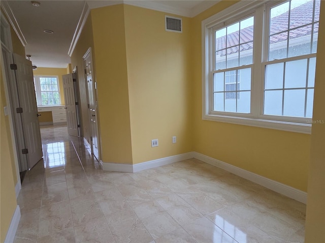 spare room with visible vents, baseboards, and crown molding