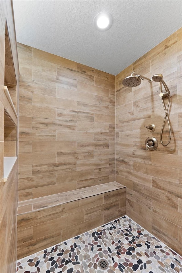 full bathroom with a tile shower and a textured ceiling