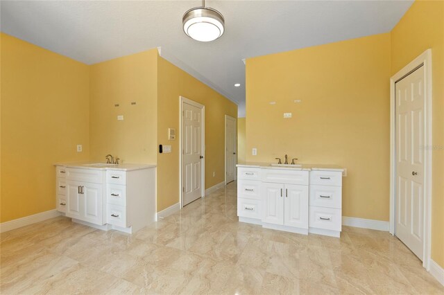 bathroom featuring two vanities, baseboards, and a sink