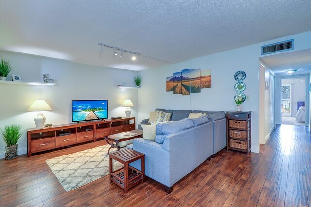 living room with dark hardwood / wood-style flooring, rail lighting, and a textured ceiling