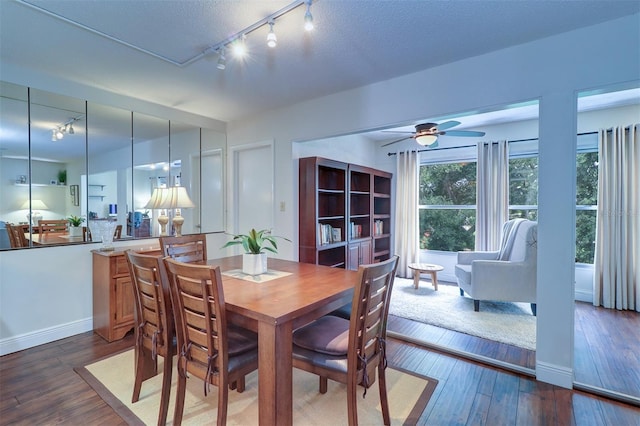 dining space featuring ceiling fan, dark wood-type flooring, rail lighting, and a textured ceiling