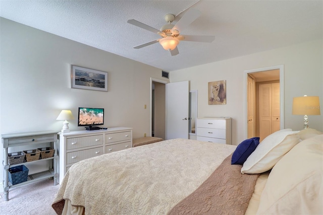 bedroom with light colored carpet, a textured ceiling, ceiling fan, and a closet