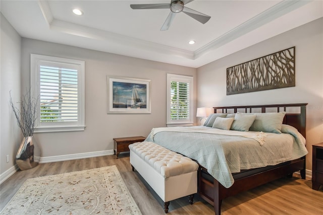 bedroom with ceiling fan, wood-type flooring, and a tray ceiling