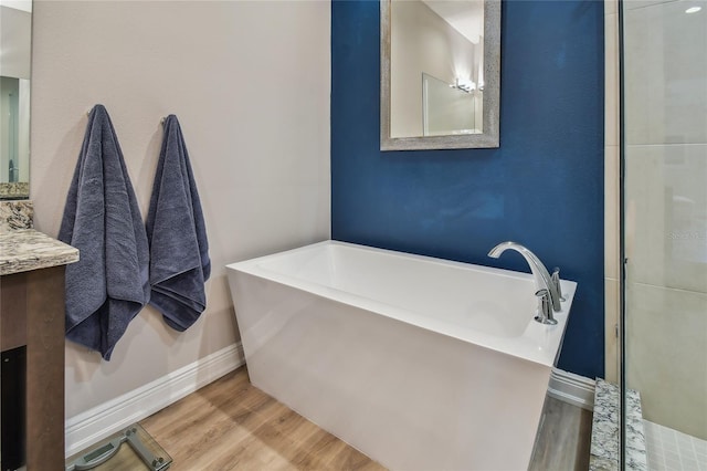 bathroom featuring vanity, hardwood / wood-style floors, and a bath