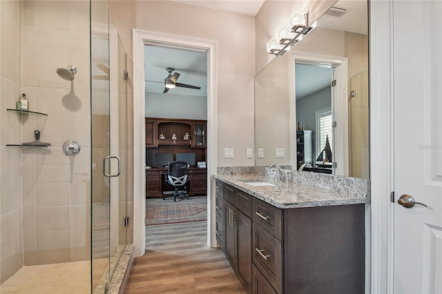 bathroom with vanity, hardwood / wood-style flooring, a shower with door, and ceiling fan