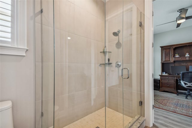 bathroom featuring hardwood / wood-style flooring, toilet, ceiling fan, and a shower with shower door