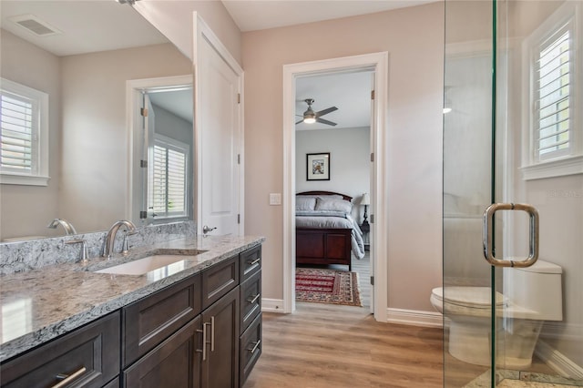 bathroom featuring toilet, a shower with shower door, vanity, ceiling fan, and hardwood / wood-style floors