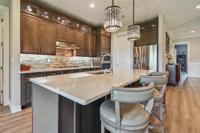 kitchen with sink, decorative light fixtures, appliances with stainless steel finishes, an island with sink, and a notable chandelier