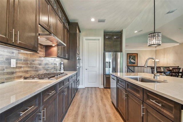 kitchen with sink, hanging light fixtures, dark brown cabinets, stainless steel appliances, and light hardwood / wood-style floors