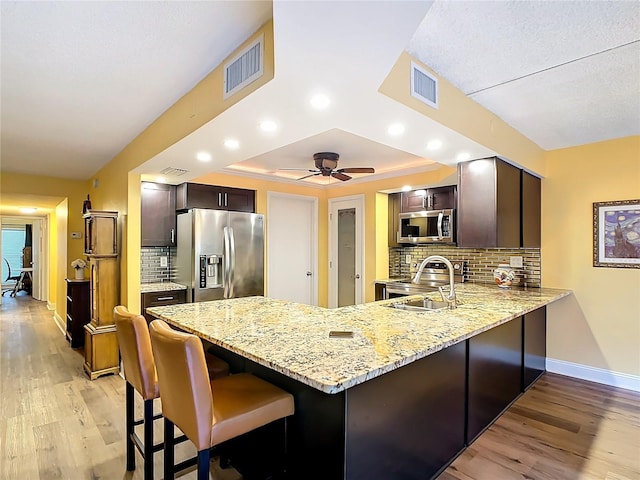 kitchen featuring sink, decorative backsplash, kitchen peninsula, and appliances with stainless steel finishes