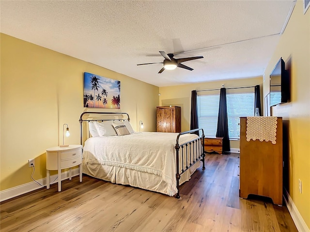 bedroom featuring hardwood / wood-style floors, a textured ceiling, and ceiling fan