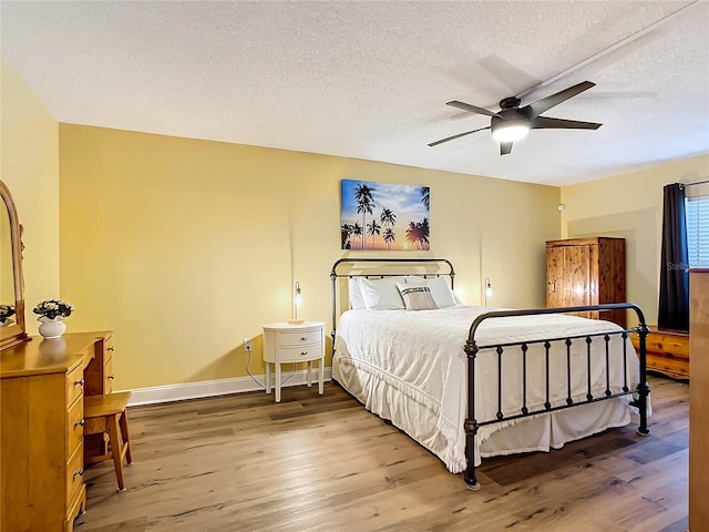 bedroom with hardwood / wood-style floors, a textured ceiling, and ceiling fan