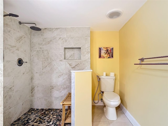 bathroom with tiled shower, toilet, and tile patterned flooring