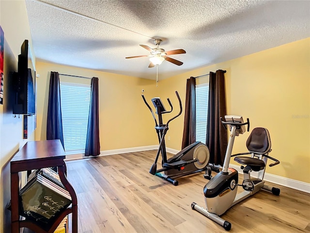 workout room featuring ceiling fan, a textured ceiling, and light hardwood / wood-style floors