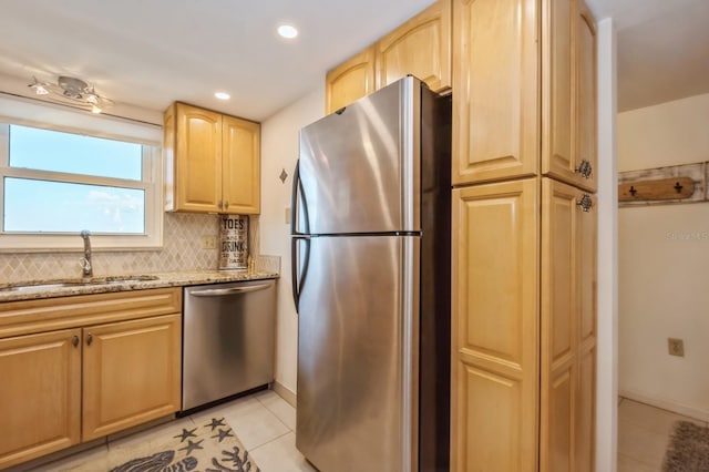 kitchen featuring sink, light tile patterned floors, appliances with stainless steel finishes, backsplash, and light stone counters