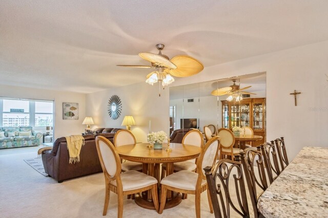 dining space featuring light carpet and ceiling fan