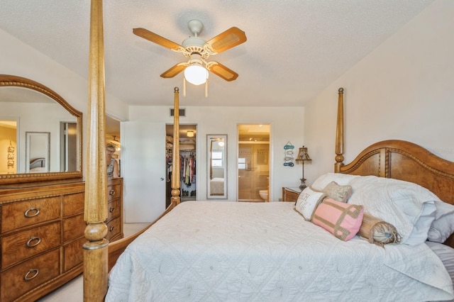 bedroom with ceiling fan, ensuite bathroom, a textured ceiling, a spacious closet, and a closet