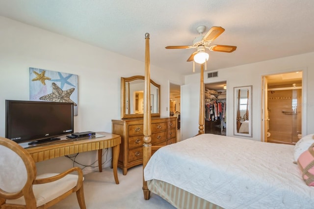 bedroom with connected bathroom, a walk in closet, light carpet, a closet, and ceiling fan