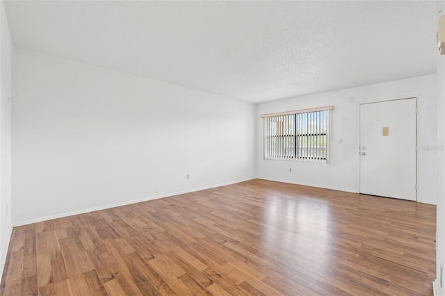 unfurnished room featuring a textured ceiling and light wood-type flooring