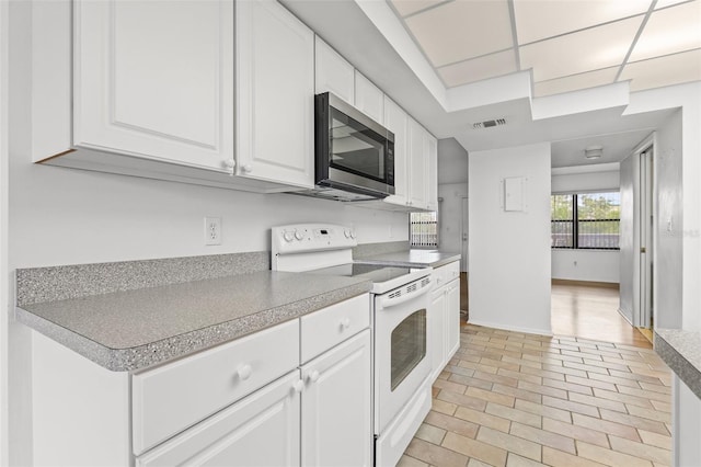 kitchen featuring electric stove, white cabinetry, and a drop ceiling