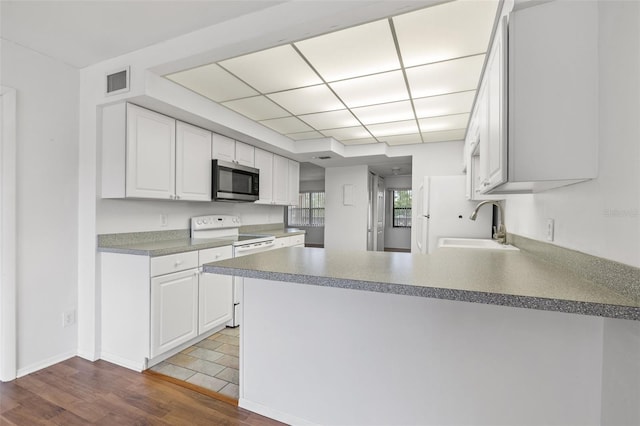 kitchen featuring white electric stove, sink, kitchen peninsula, white cabinetry, and hardwood / wood-style flooring