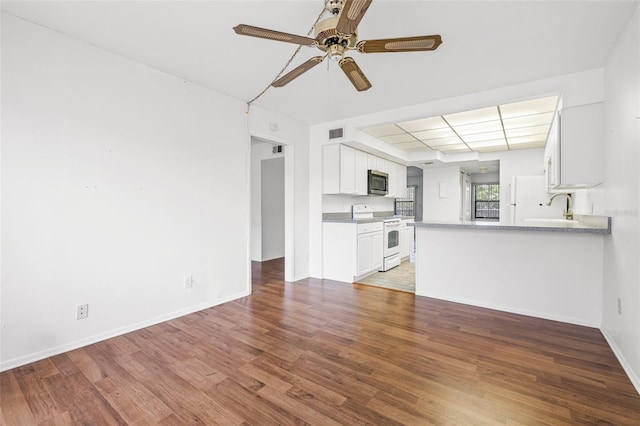 unfurnished living room featuring dark wood-type flooring and ceiling fan